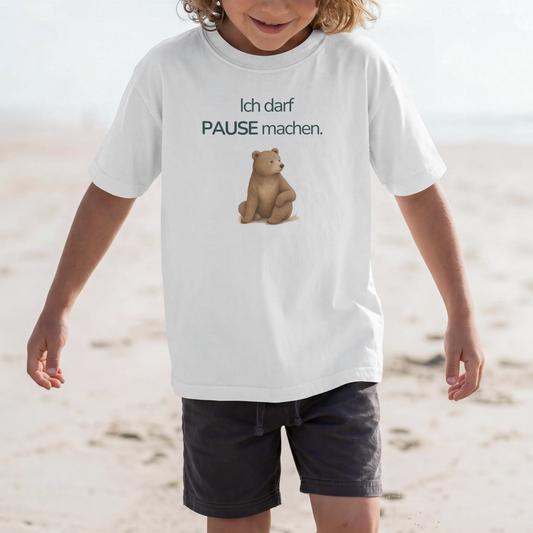 Ein Junge am Strand und er trägt ein weißes Kinder T-Shirt mit einem Bär und den Spruch Ich darf Pause machen