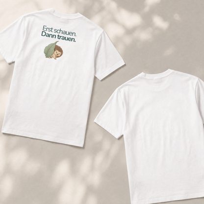 Zwei Kinder T-shirts liegen flach auf dem Boden. Die Vorderseite zeigt einen Igel mit dem Spruch Erst schauen. Dann trauen. Die Rückseite ist weiß und nicht bedruckt.