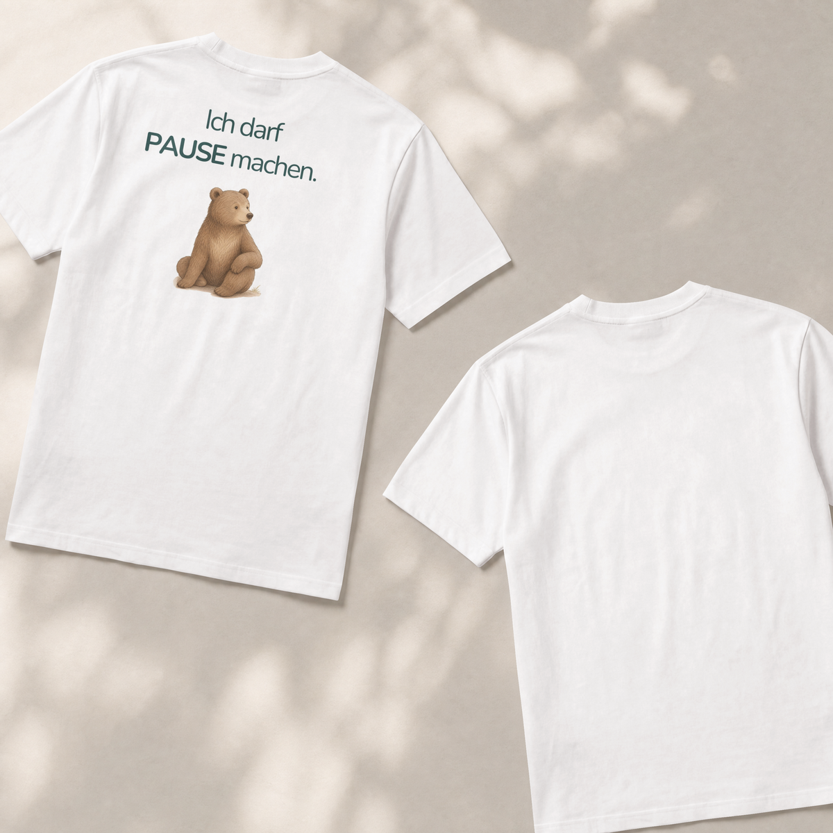 Zwei Kinder T-shirts liegen flach auf dem Boden. Die Vorderseite zeigt einen Bär mit dem Spruch Ich darf Pause machen. Die Rückseite ist weiß und nicht bedruckt.