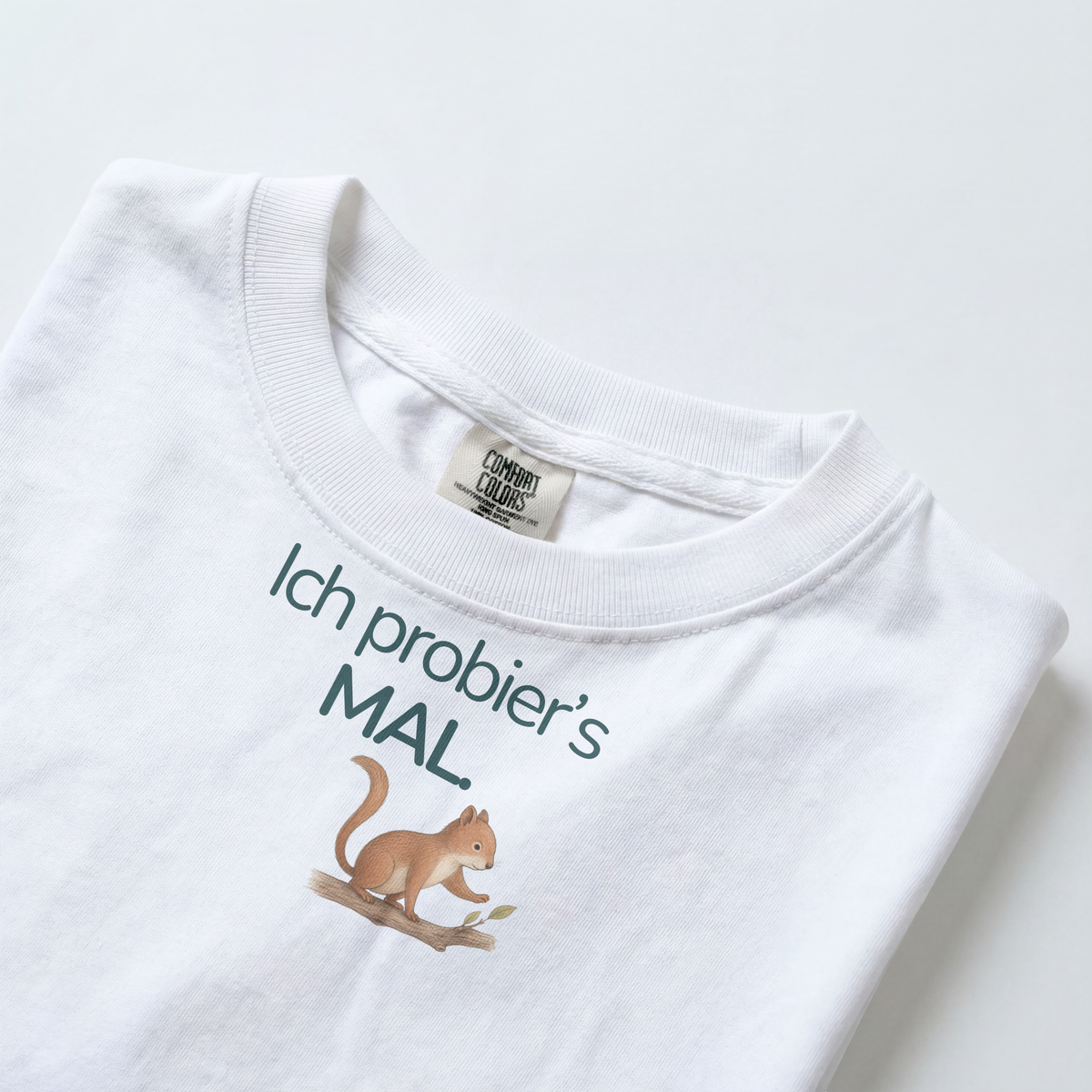 Gezeigt wird der Halsauschnitt eines weißes Kinder T-Shirts mit einem Eichhörnchen und dem Spruch Ich proebier's mal