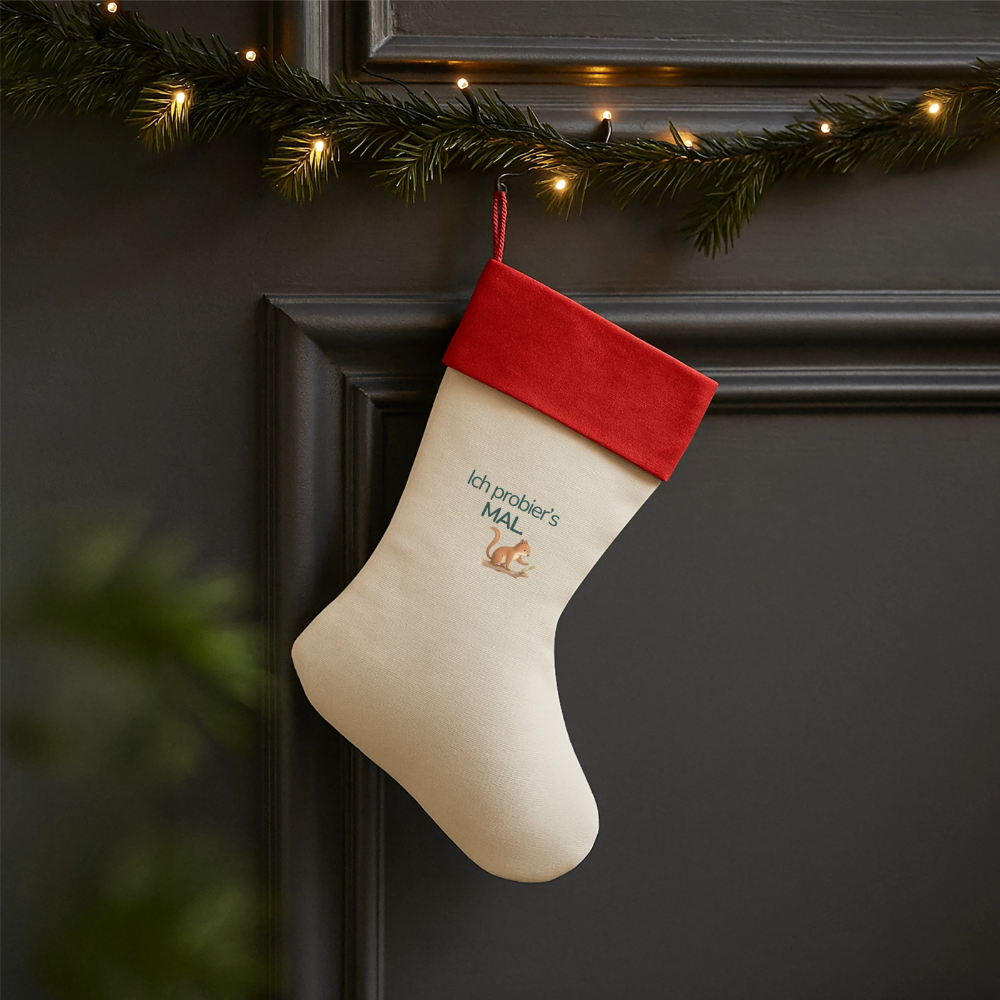 Ein Weihnachsstrumpf mit rotem Saum und der Botschaft "Ich probiers mal" und dem Motiv Eichhörnchen hängend an einer Tür.