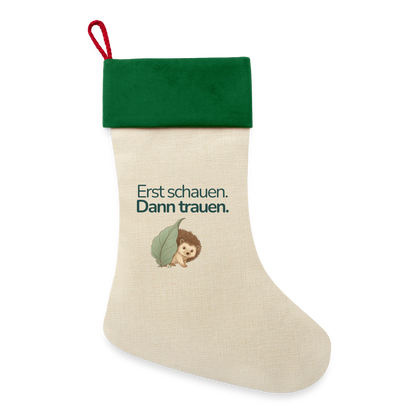 EEin Weihnachsstrumpf mit rotem Saum und der Botschaft "Erst schauen. Dann trauen." und dem Motiv Igel.