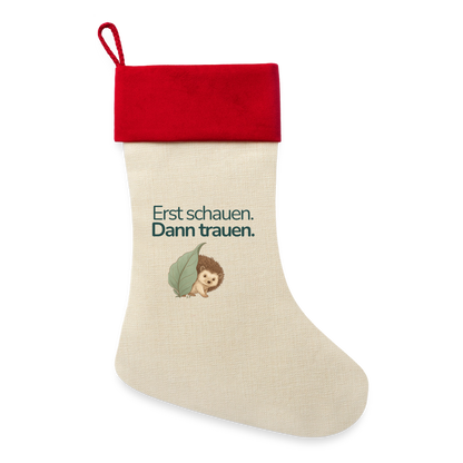 Ein Weihnachsstrumpf mit rotemSaum und der Botschaft "Erst schauen. Dann trauen." und dem Motiv Igel.